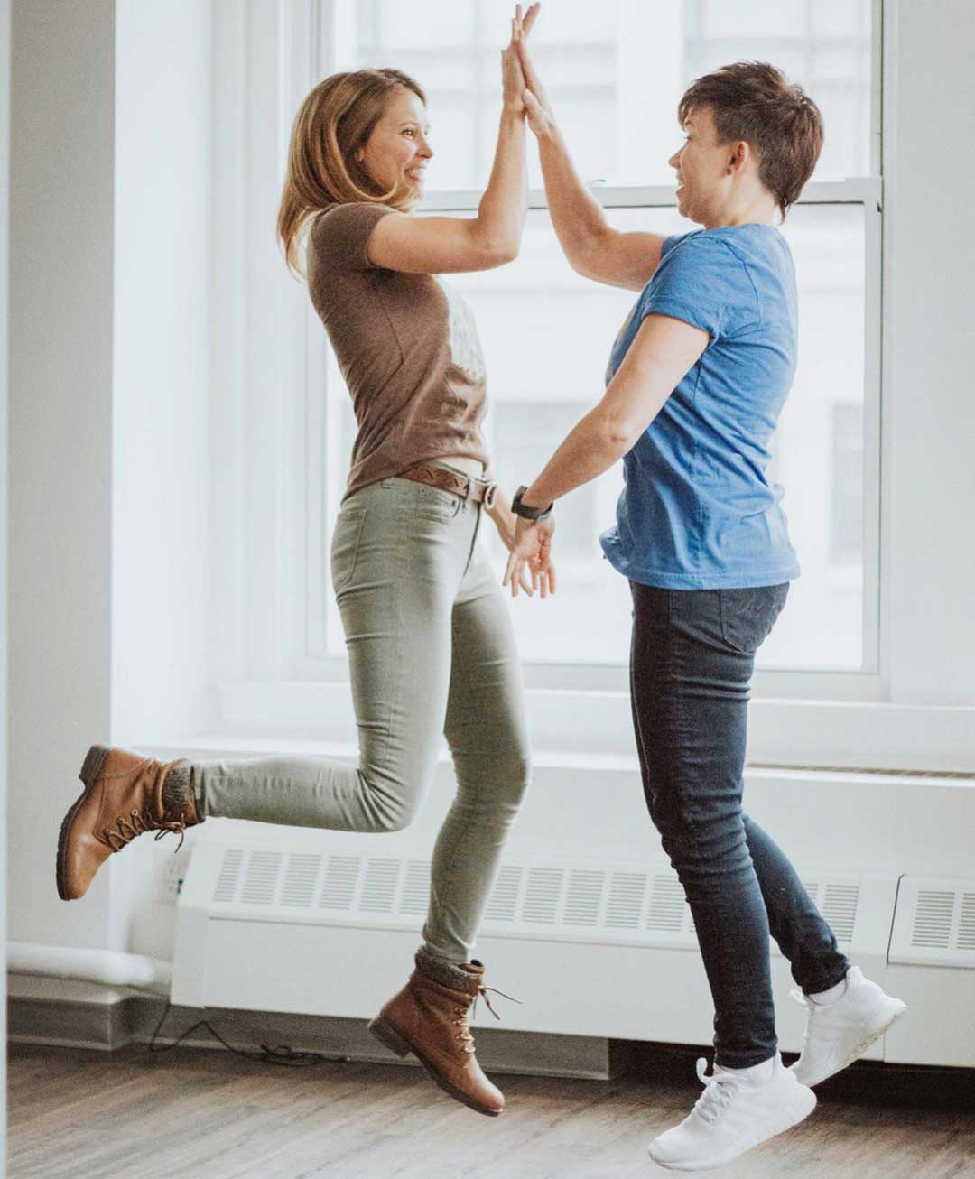 Two people high-fiving mid-air.